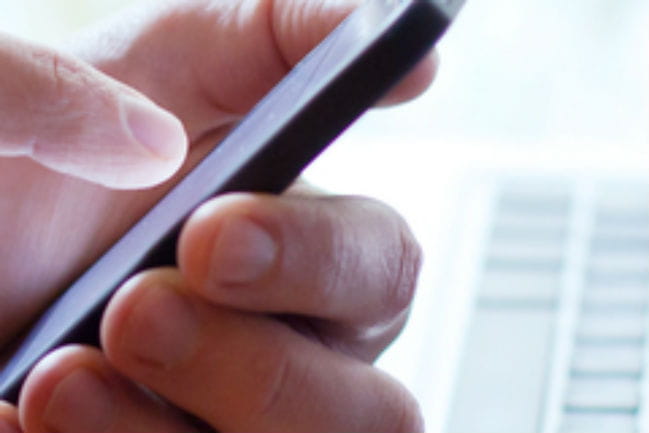 person using mobile phone and laptop