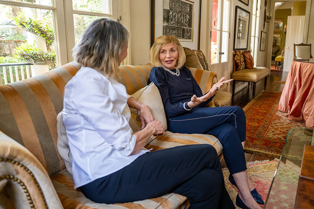 two elegant women chat on a sofa