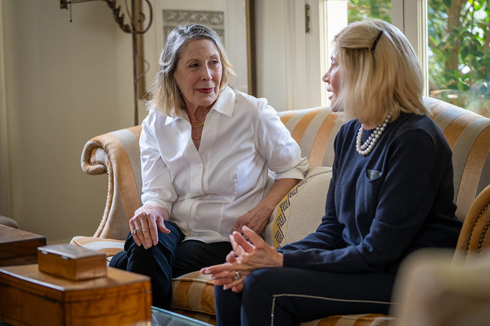 two elegant women sit on a sofa and chat