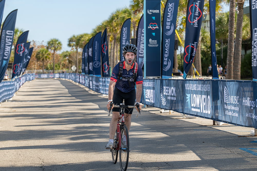 a man lets out a whoop as he crosses the finish line in a bike ride