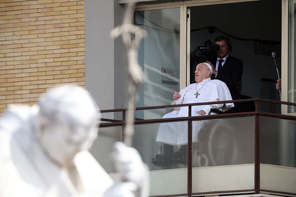 Man in white papal robe and cap is wheeled out of a building.