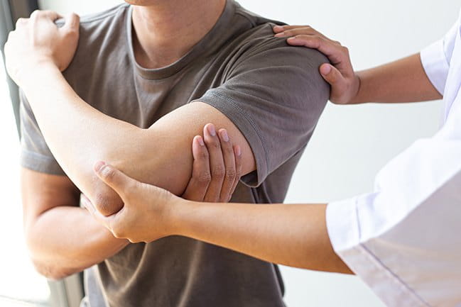 A doctor examines a person with shoulder pain.